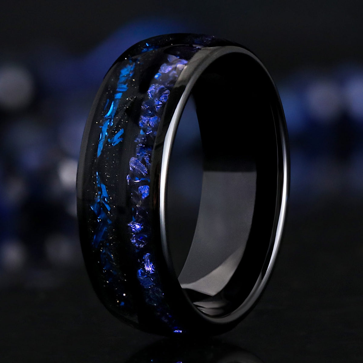 Men's 8mm black tungsten ring with crushed blue sapphire and blue foil inlays, standing at an angle