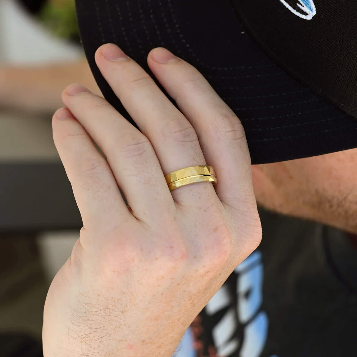 Men's 7mm hammered gold tungsten band worn on a hand