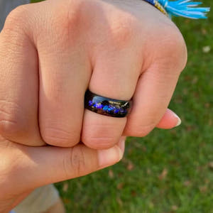Men's black tungsten ring with galaxy opal inlay, worn on a hand
