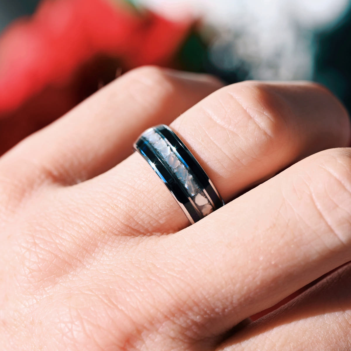 Silver tungsten pearl and black onyx ring worn on a man's finger, angled view