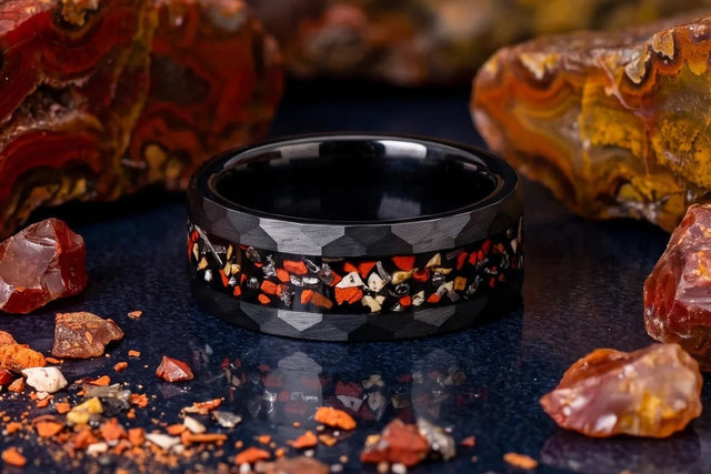 Hammered black tungsten band with dinosaur bone inlay beside agatized fossil pieces