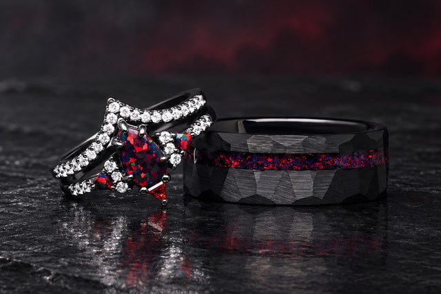 Black fire opal couples ring set on dark slate: her shield-cut red opal ring beside his hammered black tungsten band