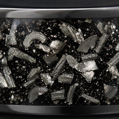 Close-up of crushed meteorite inlay in a polished black tungsten band