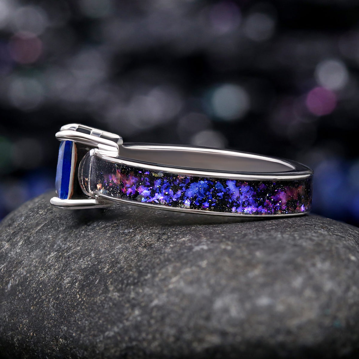 Sterling silver sapphire ring lying on its side, showing the Orion nebula inlay along the band